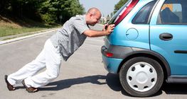 Чоловік штовхає авто